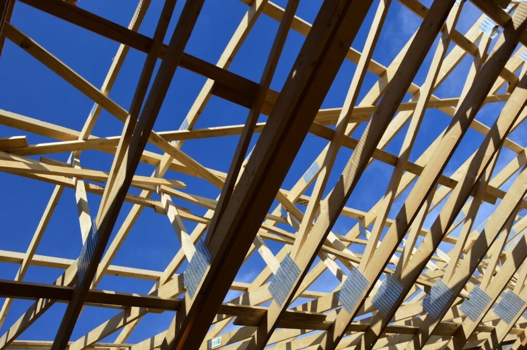 View of wooden roof trusses during construction with clear blue sky background.